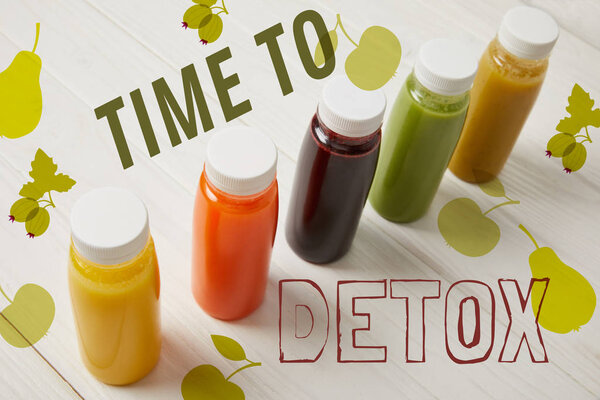 detox smoothies in bottles standing in row on white wooden background, time to detox inscription