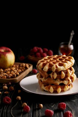 fındık ile plaka üzerinde taze pişmiş Belçika Waffle ve ahududu siyah ahşap masa üzerinde yığını