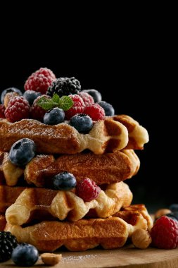 Siyah ahşap kesme tahtası üzerinde çilek ile lezzetli yığılmış Belçika Waffle