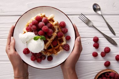 Kırpılan atış tabak lezzetli Belçika Waffle Beyaz ahşap masa üzerinde tutan kadın