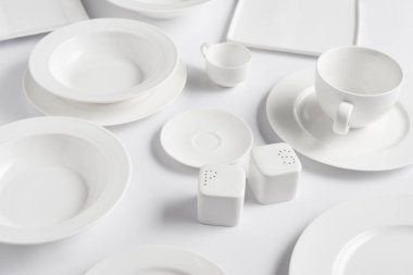 beyaz masa üzerinde farklı tabak, kupa, kase, saltcellar ve biber tekeri görünümü kadar kapatın 