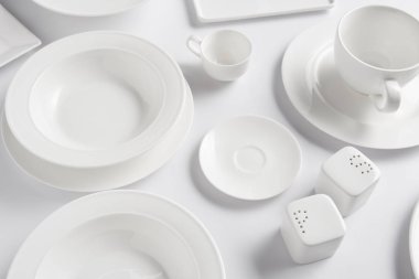beyaz masa üzerinde farklı tabak, kupa, kase, saltcellar ve biber tekeri yüksek açılı görünüş 