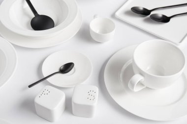 saltcellar, biber tekeri, salata kaşık, kaşık, kase, kupa ve çeşitli plakaları beyaz tablo görünümünü kapat
