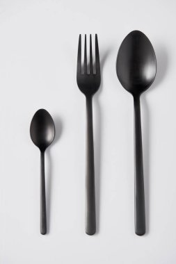 elevated view of black spoons and fork on white background, minimalistic concept clipart