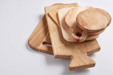 close up image of stack of different wooden cutting boards on white table clipart