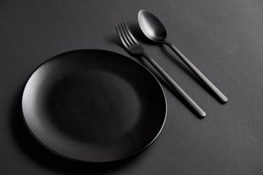 siyah tablo, minimalist kavramı üzerinde siyah kaşık, çatal ve plaka yüksek açılı görünüş