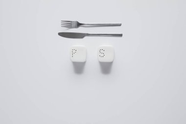 top view of fork, knife, saltcellar and pepper caster on white table, minimalistic concept clipart