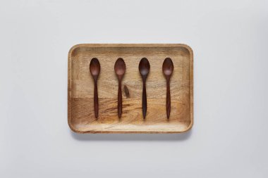 tahta kaşıklar ile ahşap tepsi üstten görünüm beyaz masa, minimalist kavramı üzerinde