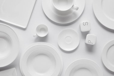 beyaz masa üzerinde farklı tabak, kase, saltcellar, biber tekeri ve Kupası üstten görünüm