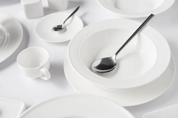 在白桌上的勺子 不同的盘子和杯子的选择性聚焦 — 图库照片