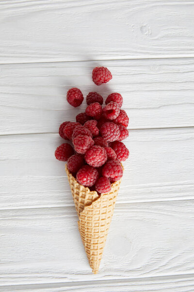 top view of waffle cone with raspberries on wooden table 