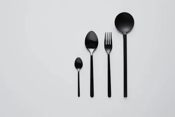 各種スプーン フォーク サラダ スプーン白いテーブル ミニマルなコンセプトの黒の平面図します — ストック写真
