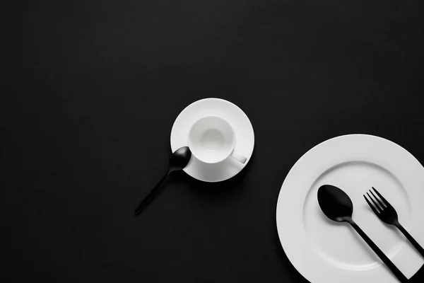 黒いテーブルの上の皿 カップ 黒スプーンとフォーク トップ ビュー — ストック写真