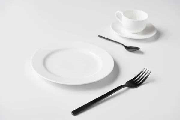 Selective focus of plate, fork, spoon and cup on white table — Stock Image Selective Focus Plate Fork Spoon Cup White Table Royalty Free Stock Images