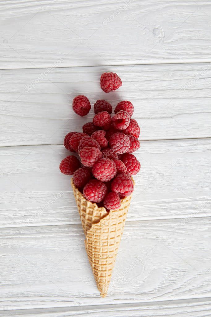 top view of waffle cone with raspberries on wooden table 