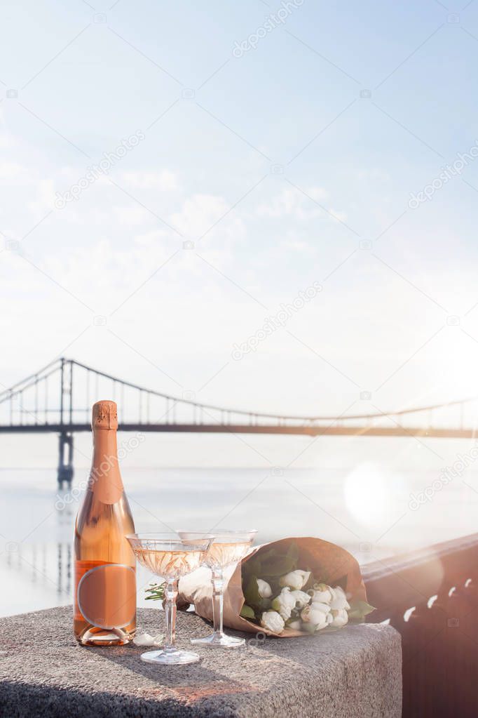 close-up view of beautiful bouquet of flowers, glasses and bottle of champagne at riverside 