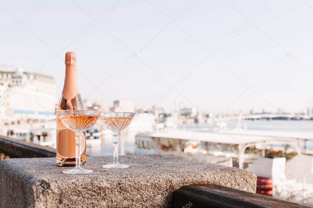 close-up view of two glasses and bottle of champagne on embankment at riverside 