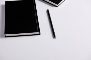 close-up shot of black hard cover notebooks with pencil on white surface clipart