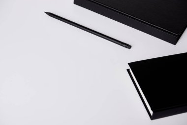 close-up shot of black hard cover notebooks with pencil on white tabletop clipart