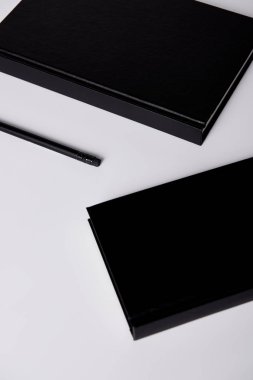 close-up shot of black notebooks with pencil on white tabletop for mockup clipart