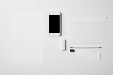 boş ekran ve ofis malzemeleri ile smartphone üstten görünüm mockup için beyaz masa üzerinde
