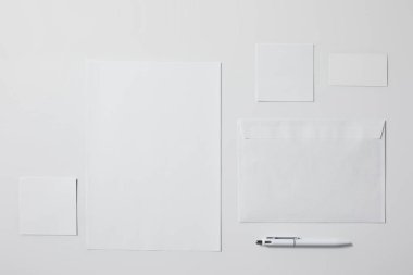 top view of various paper objects with pen on white surface for mockup clipart