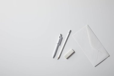 top view of envelope with pen and pencil on white surface for mockup clipart