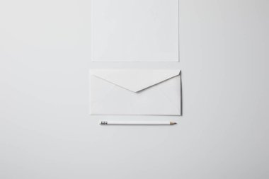 top view of envelope with blank paper and pencil on white surface for mockup clipart