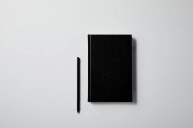 top view of black notebook with pencil on white surface for mockup clipart
