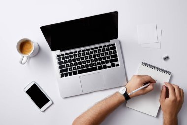 İşyerinde Not defterinizdeki gadget'lar ve kahve fincanı ile mockup için beyaz yüzey üzerinde yazma adam resmini kırpılmış