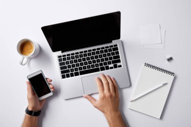 laptop ile çalışma ve smartphone mockup için beyaz yüzey üzerinde elinde tutan adamın kırpılmış atış