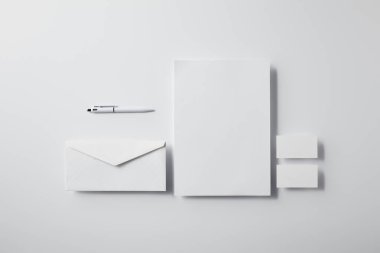kalem, boş kağıt ve iş kartları ile katmanlı zarf üstten görünüm mockup için beyaz yüzeyi