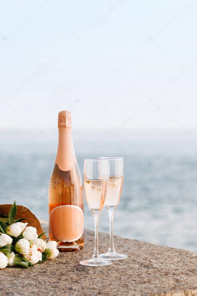 close-up view of beautiful bouquet of flowers and champagne in glasses and bottle on embankment