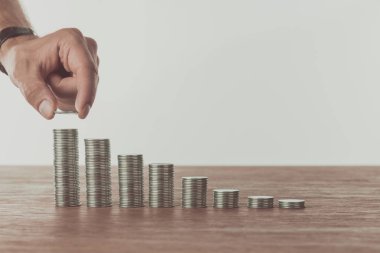 cropped image of man stacking last coin on wooden table, saving concept clipart