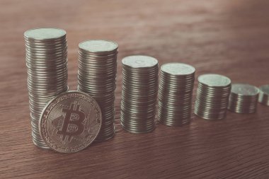 bitcoin near stacks of coins on tabletop, saving concept clipart