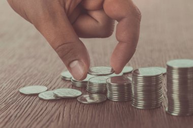 cropped image of man stacking coins on wooden surface, saving concept clipart