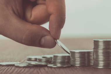 cropped image of man stacking coins on wooden table, saving concept clipart