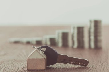 key with trinket near stacks of coins on tabletop, saving concept clipart