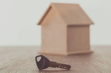 key and small house on wooden table, saving concept  clipart