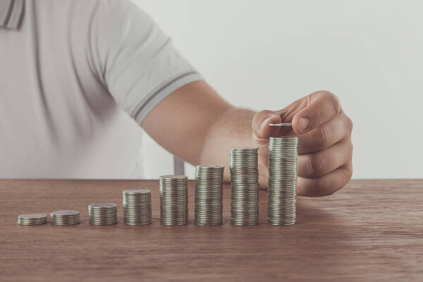 cropped image of man stacking coins on tabletop, saving concept