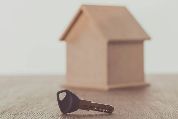 key and small house on wooden table, saving concept 