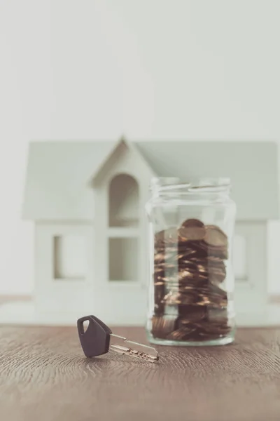 Chave Perto Frasco Moedas Mesa Com Pequena Casa Fundo Economizando — Fotografia de Stock