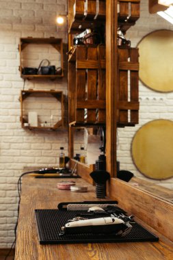 professional barber tools on wooden shelf and mirror at modern barbershop clipart
