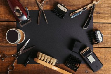 top view of various professional barber tools on black card on wooden surface clipart
