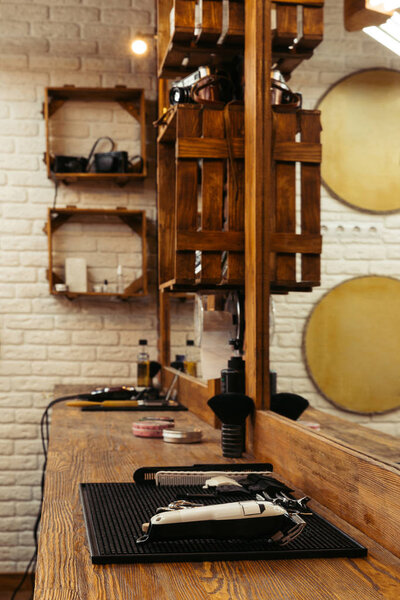 professional barber tools on wooden shelf and mirror at modern barbershop