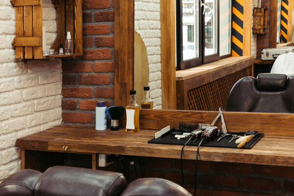 professional barber tools on wooden shelf near mirror in modern barbershop