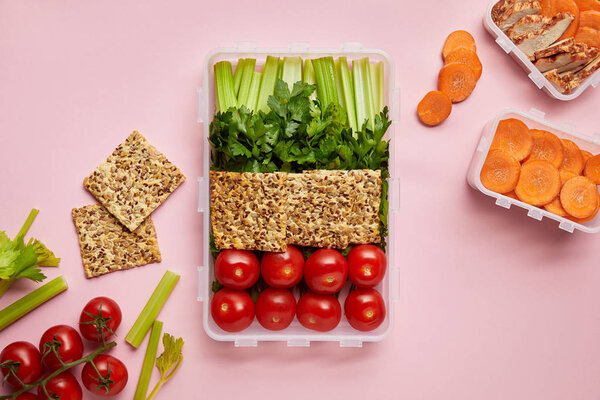 flat lay with healthy food arranged in food containers isolated on pink