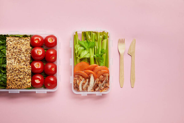 flat lay with healthy food arranged in food containers and cutlery isolated on pink