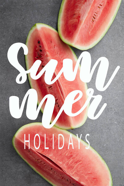 flat lay with red watermelon pieces on grey concrete tabletop, with "summer holidays" lettering