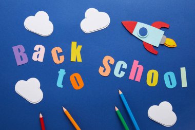 kurşun kalem, bulutlar ve roket üzerinde mavi arka plan ile yazı okula geri üstten görünüm